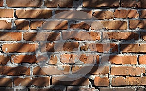 Roughly built red brick wall covered in shadow
