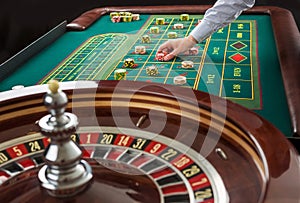 Roulette and piles of gambling chips on a green table.