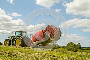 A round baler pulled by a John Deere during harvesting