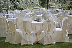 Round banqueting tables and chairs set up in the garden for wedding lunch photo