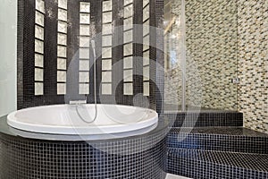 Round bathtub inside black bathroom