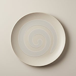 A round, beige ceramic plate with a smooth texture sits against a neutral, light