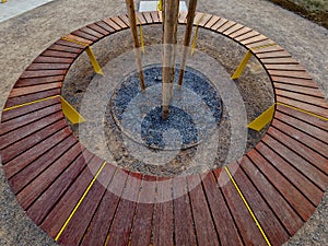 round bench made of wood encloses a tree, sitting around with