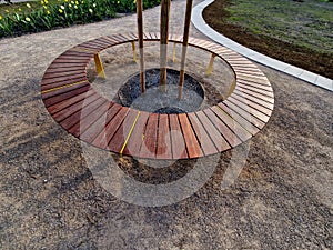 round bench made of wood encloses a tree, sitting around with wood