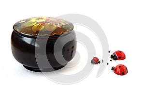 Round black casket and wooden ladybugs on a white background