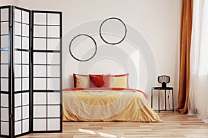 Round black frames on white wall of elegant bedroom interior with king size bed with yellow and ginger bedding