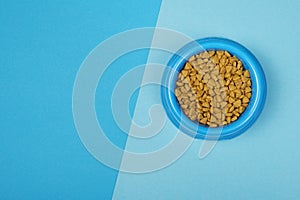 Round Blue food bowl with cat kibble seen from a high angle view