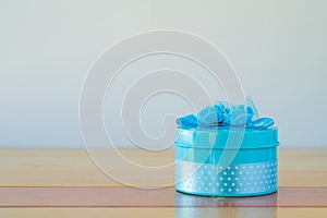 Round blue gift box with ribbon bow on wooden table with copy sp