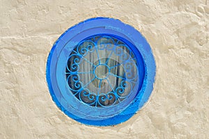 Round blue window and bar with arabic pattern . Wall of a house in Sidi Bou Said, Tunisia