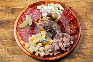 Round board with various antipasti appetizers. Cheese, salami, olives, nut mix and sun-dried tomatoes. top view
