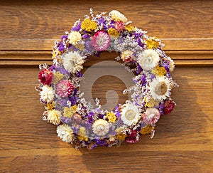 A round bouquet of colorful, vibrant dried flowers on an old wooden door. Autumn decoration