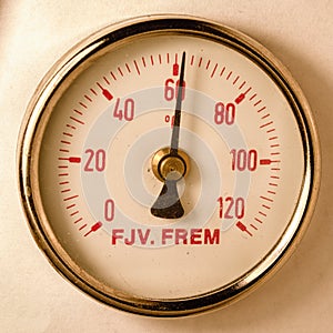 A round brass temperature meter on the incoming water to a district heating system