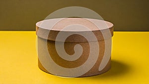 Round brown cardboard box on yellow table. Mock up. Packaging for delivery. Eco package