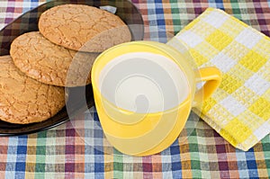 Round brown cookies in black dish and cup of milk