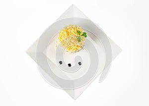 Round calad with grated cheese and sauce on a white square plate top view, on white background