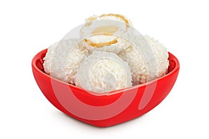 round candy raffaello with coconut flakes and nut in ceramic bowl isolated on white background photo