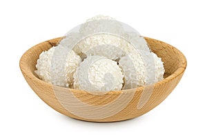 round candy raffaello with coconut flakes and nut in wooden bowl isolated on white background