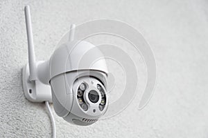 Round CCTV camera with antennas shoots video on the white wall