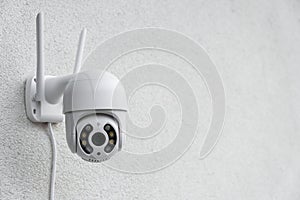 Round CCTV camera with antennas shoots video on the white wall