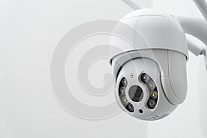 Round CCTV camera with antennas shoots video on the white wall