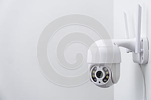 Round CCTV camera with antennas shoots video on the white wall