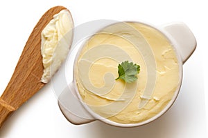 Round ceramic dish filled with butter next to a wooden knife on