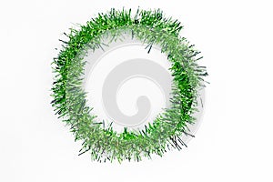 Round circle of bright green tinsel on a white background. Christmas decorations. New year photo
