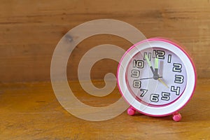 A round clock stands on a wooden shelf