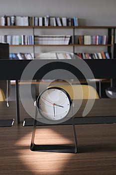Round clock on table against a library background