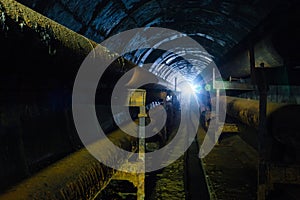 Round concrete underground tunnel of heating duct system with rusty pipes