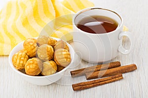 Round cookies in bowl, napkin, cup of tea, cinnamon stick