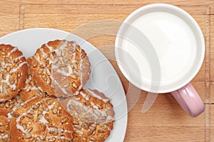 Round cookies with sunflower and sesame seeds, milk in pink mug, top view. Valuable breakfeast.