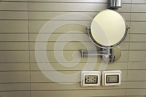 Round cosmetic mirror on wall with Electric white socket in the bathroom.