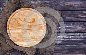 Round cutting board on old wooden texture background. Top view