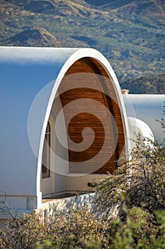 Round cylinder building with white stucco facade and wooden internal lining with panoramic glass sliding window