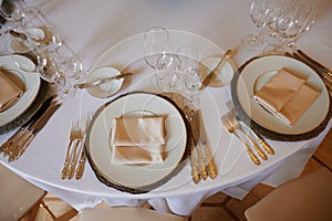 A round dining table with a white tablecloth and cloth napkins is prepared for a banquet for several persons