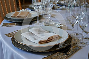 A round dining table with a white tablecloth and cloth napkins is prepared for a banquet for several persons photo