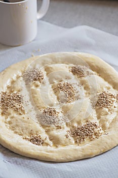 Round dough on a table, preparing ramadan pide with sesame seeds