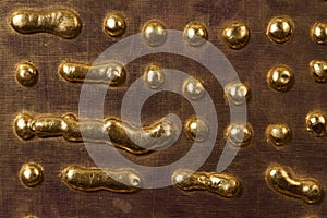 Round drops and drips of gold metal on the surface of the board