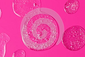 Round drops of white gel with bubbly texture.Jelly texture of antibacterial liquid with bubbles iside.Bright pink background with