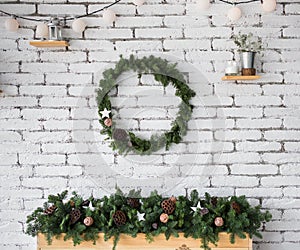 Round elegant Christmas wreath hanging on white brick wall