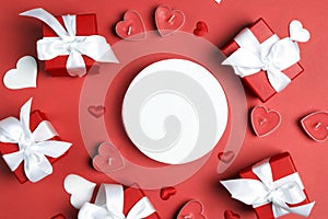 Round empty greeting card surrounded by gifts, hearts and candles on a red background.