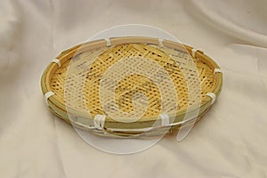 Round empty handmade bamboo sieve with green trim and crosshatching. Basket art photo