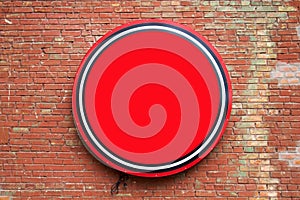 Round empty red banner hanging on a brick wall