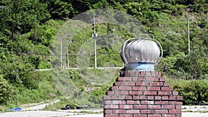 Round exhaust vent rotating on top of red brick chimney