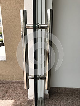 Round finished stainless steel pipe door handles with accessories fixed into glass door for an entrance of an building and