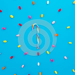 Round frame of colored candies and rainbow cane sugar on blue background. Flat lay, top view