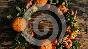 Round frame made of autumn vegetables and fruits on wooden background.