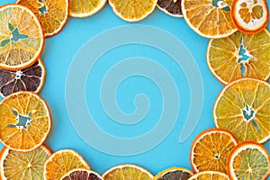 Round frame made of dehydrated citruses as lemons, oranges and tangerines on blue background with copy space