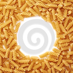 Round frame made of dry rotini pasta over isolated white background